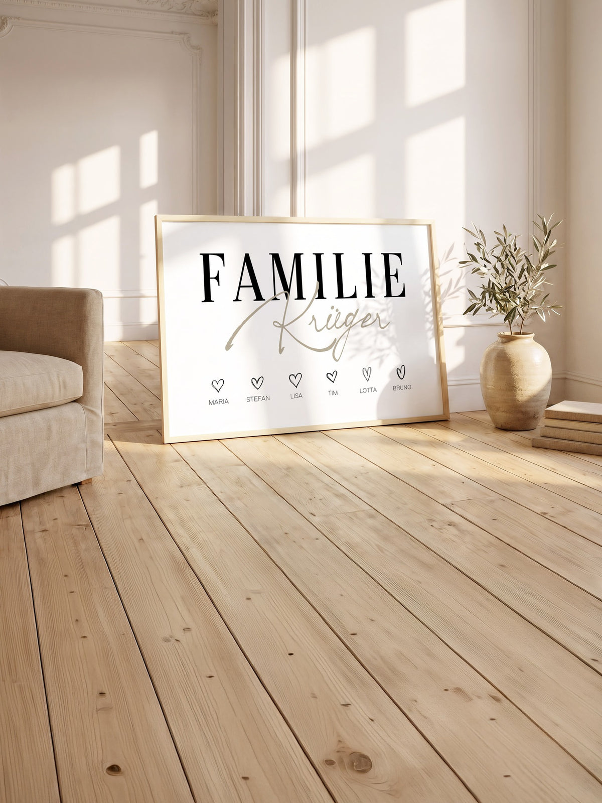 Großes Familienposter mit sechs Herzen im hellen Holzrahmen auf alten Holzdielen im Altbau, daneben ein Leinensessel
