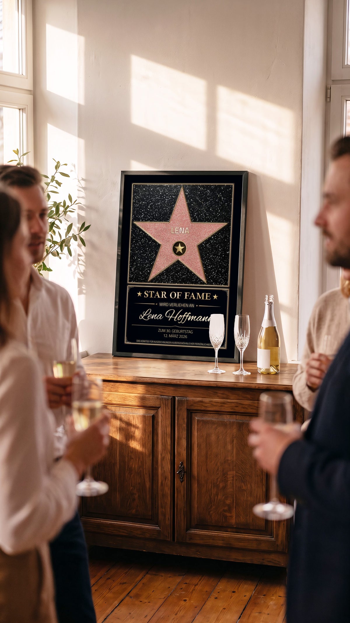 Star-of-Fame-Poster mit Stern und Wunschname auf einer Holzanrichte, daneben Sekt; Gäste feiern im Hintergrund