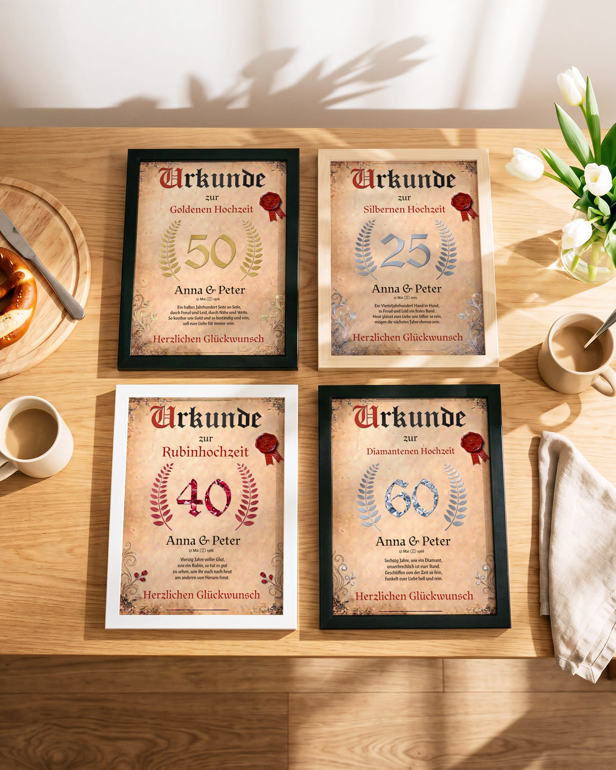Vier Urkunden zur Silberhochzeit, Rubinhochzeit, Goldenen und Diamantenen Hochzeit auf einem Frühstückstisch, Zahl und Kranz je in der Farbe des Jubiläums
