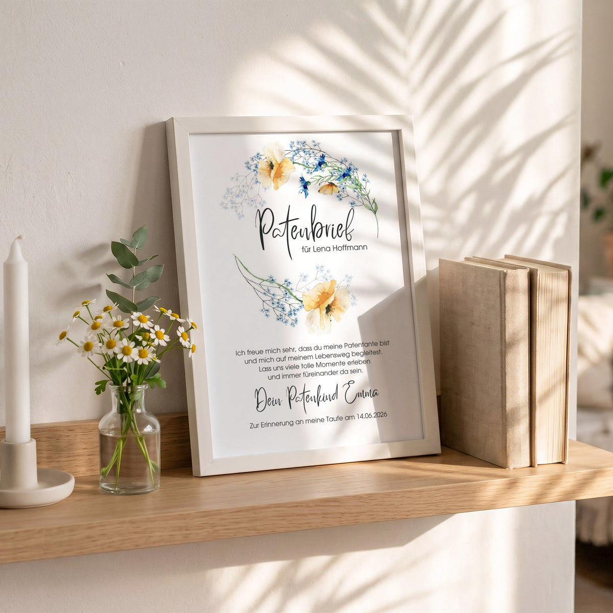 Patenbrief Blumen im weißen Holzrahmen auf einem Wandregal neben Taufkerze und Kamille