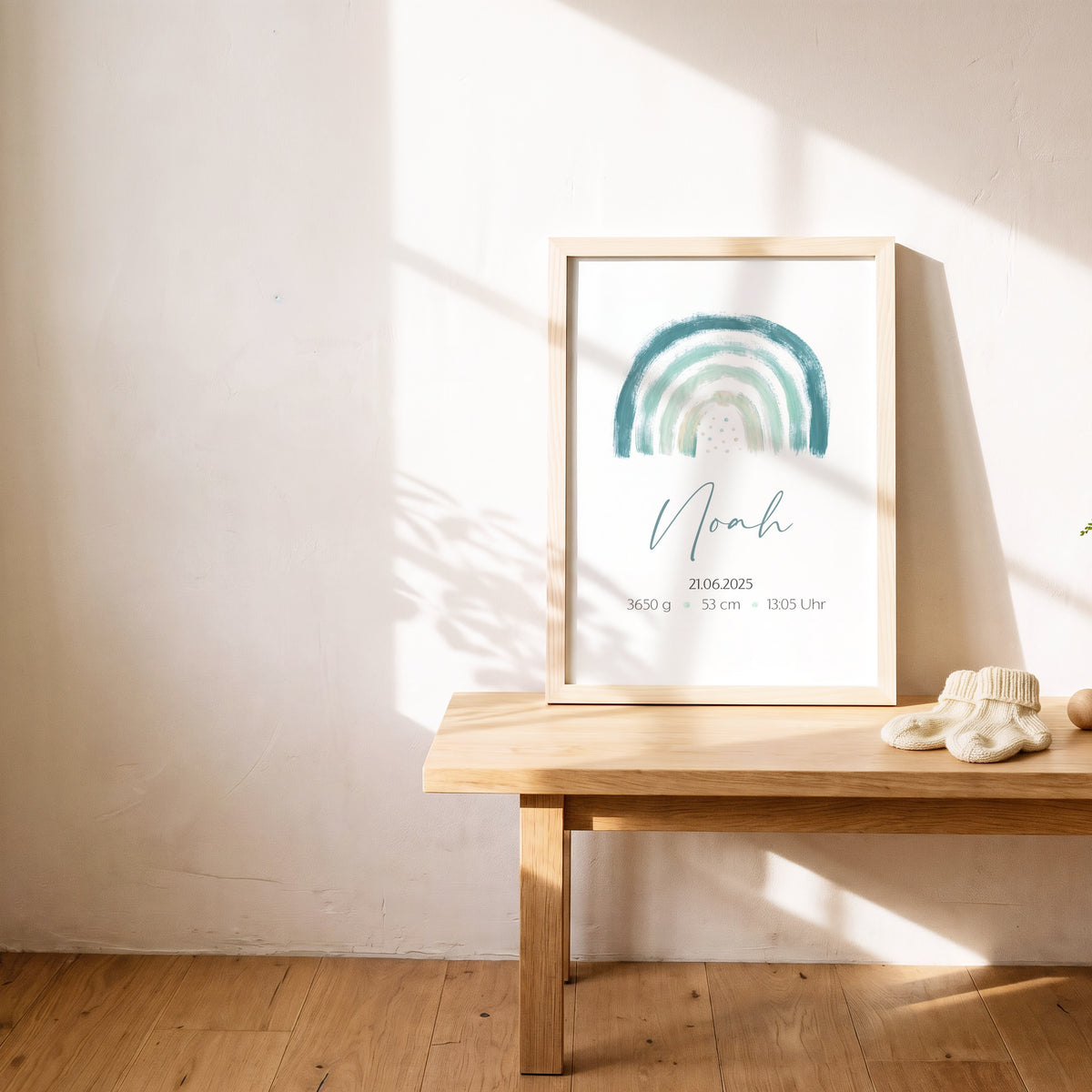 Geburtsposter mit grünem Regenbogen im hellen Holzrahmen auf einer Bank: Name, Geburtsdatum, Gewicht, Größe und Uhrzeit