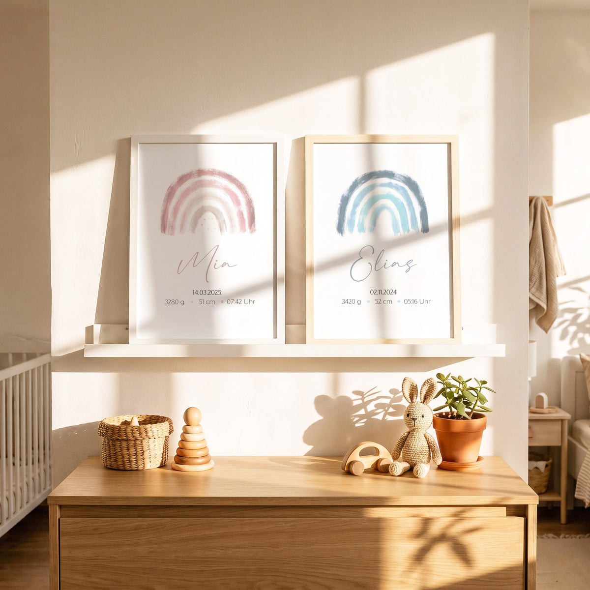 Zwei Geburtsposter für Geschwister in Rosa und Blau nebeneinander auf einer Bilderleiste im Kinderzimmer