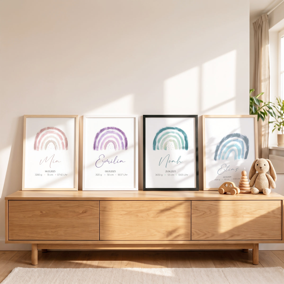 Vier Geburtsposter nebeneinander auf einem Sideboard, Regenbogen in Rosa, Lila, Grün und Blau