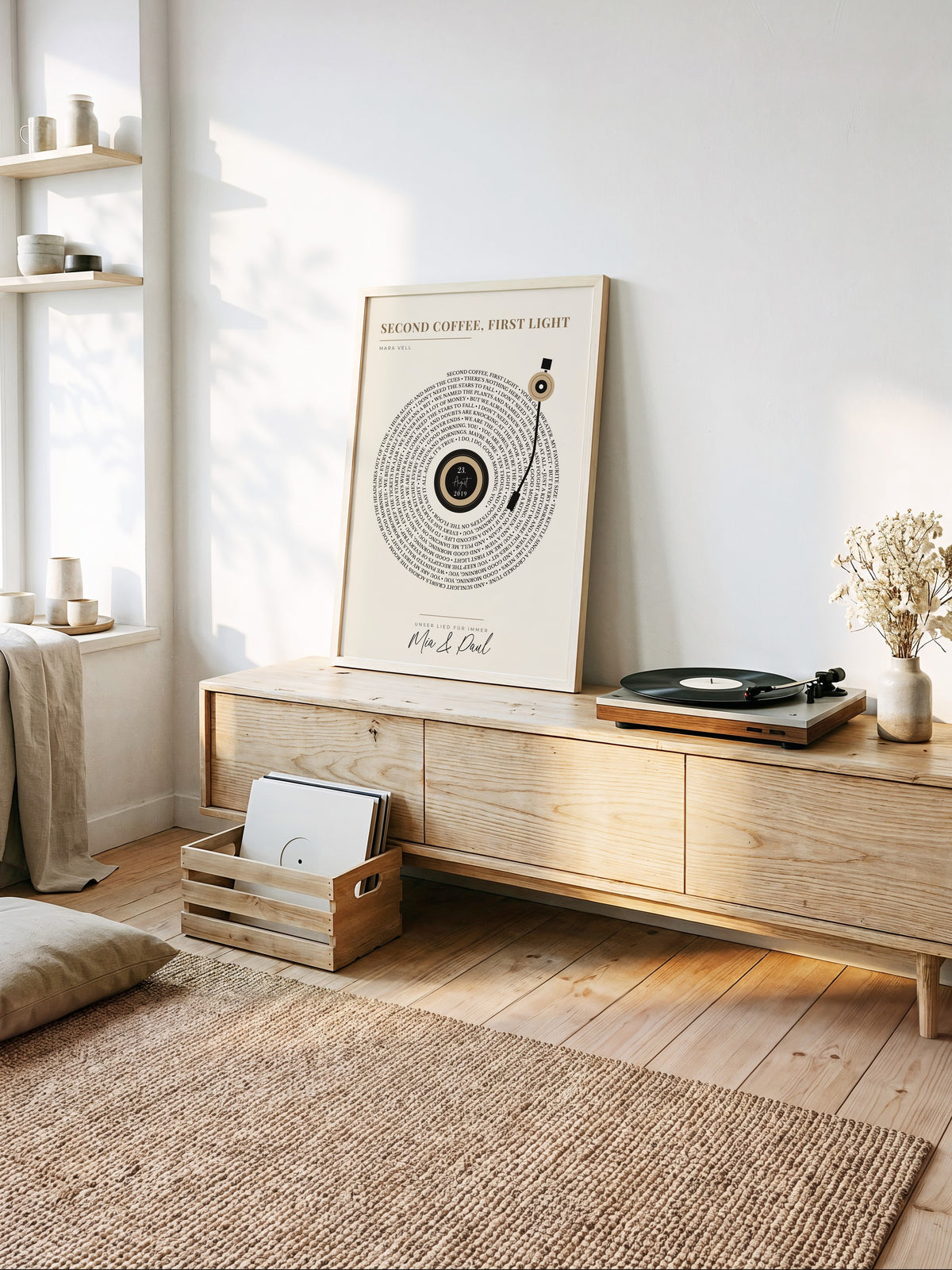 Songtext-Poster als Schallplatte in Sand im hellen Holzrahmen auf einem Sideboard neben einem Plattenspieler im sonnigen Wohnzimmer