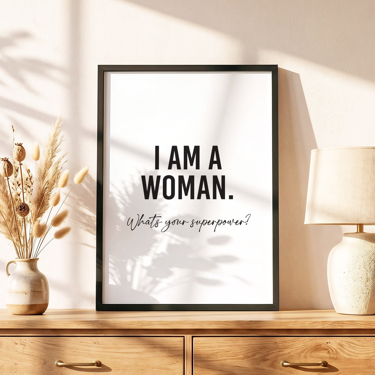 Spruchposter I am a woman im schwarzen Holzrahmen auf einer Kommode