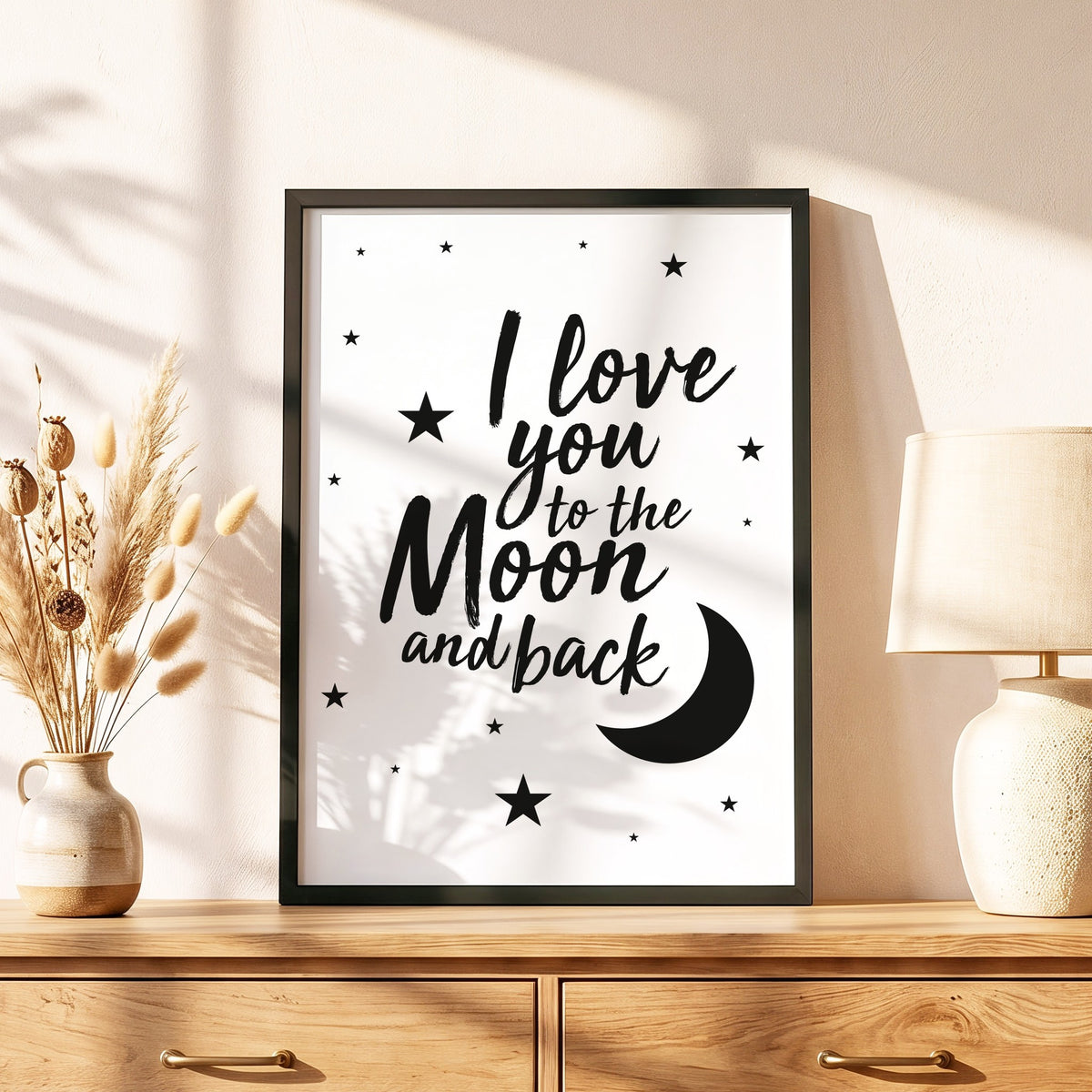 Spruchposter I love you to the moon and back im schwarzen Holzrahmen auf einer Kommode
