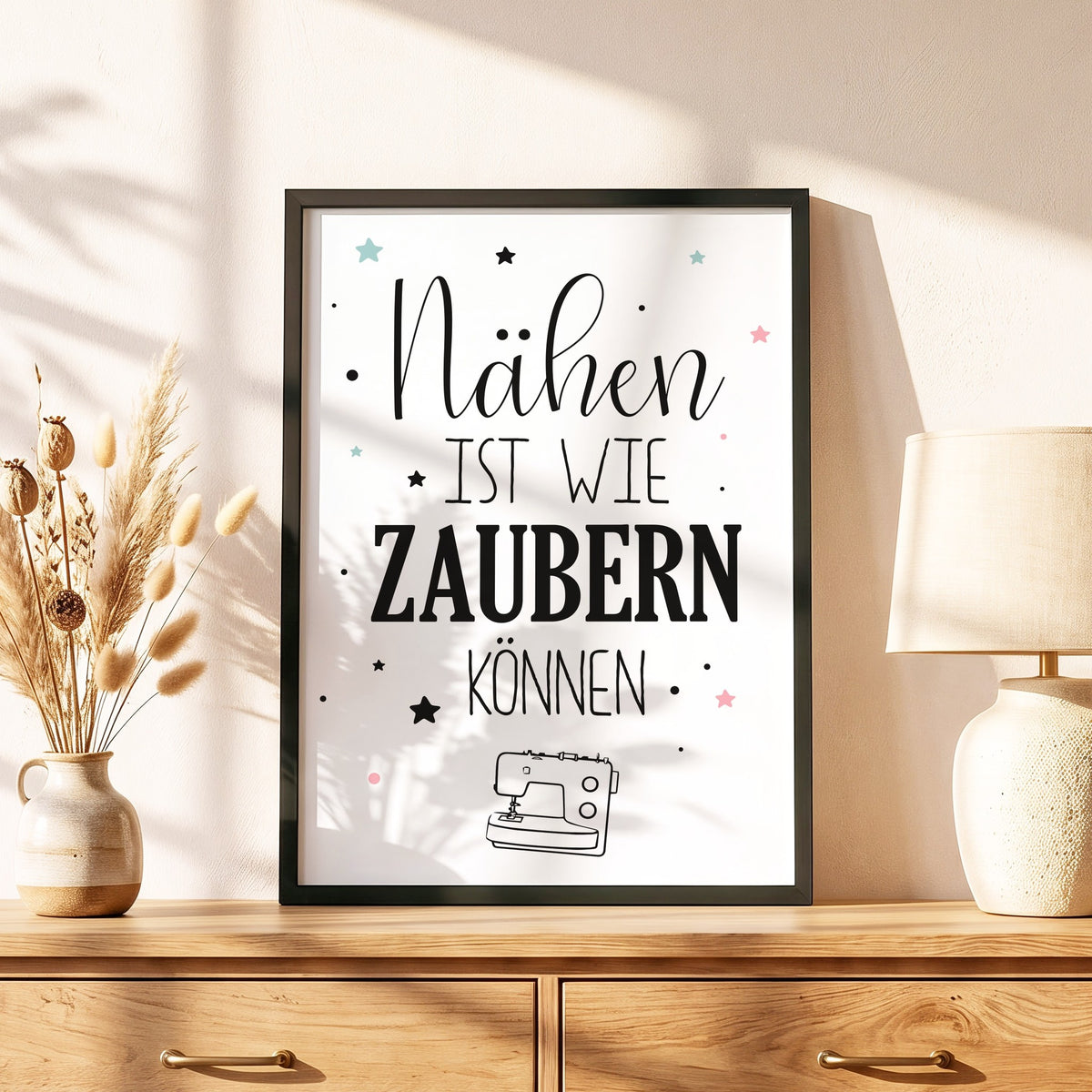 Spruchposter Nähen ist wie zaubern können im schwarzen Holzrahmen auf einer Kommode