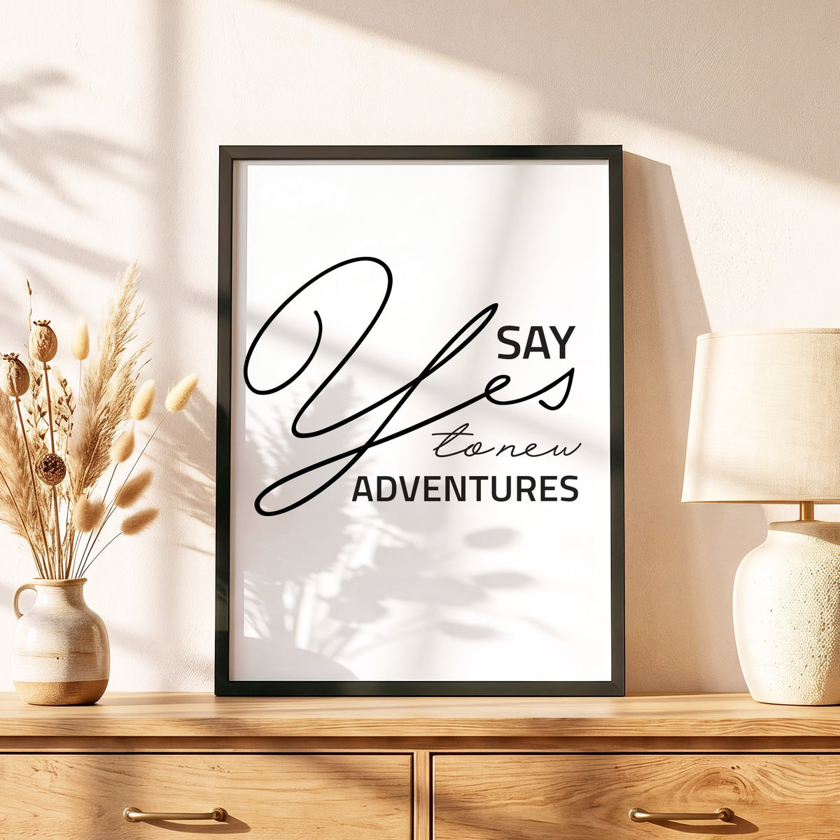 Spruchposter Say yes to new adventures im schwarzen Holzrahmen auf einer Kommode