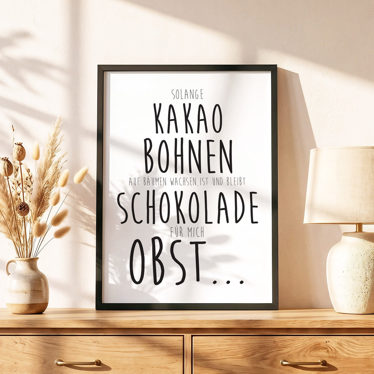 Spruchposter Schokolade ist Obst im schwarzen Holzrahmen auf einer Kommode