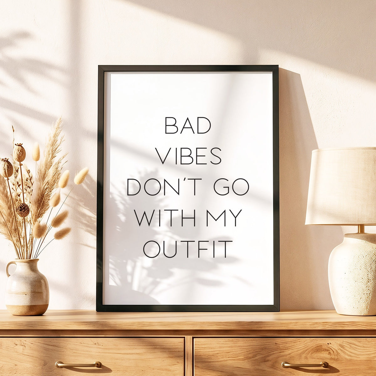 Spruchposter Bad vibes don't go with my outfit im schwarzen Holzrahmen auf einer Kommode