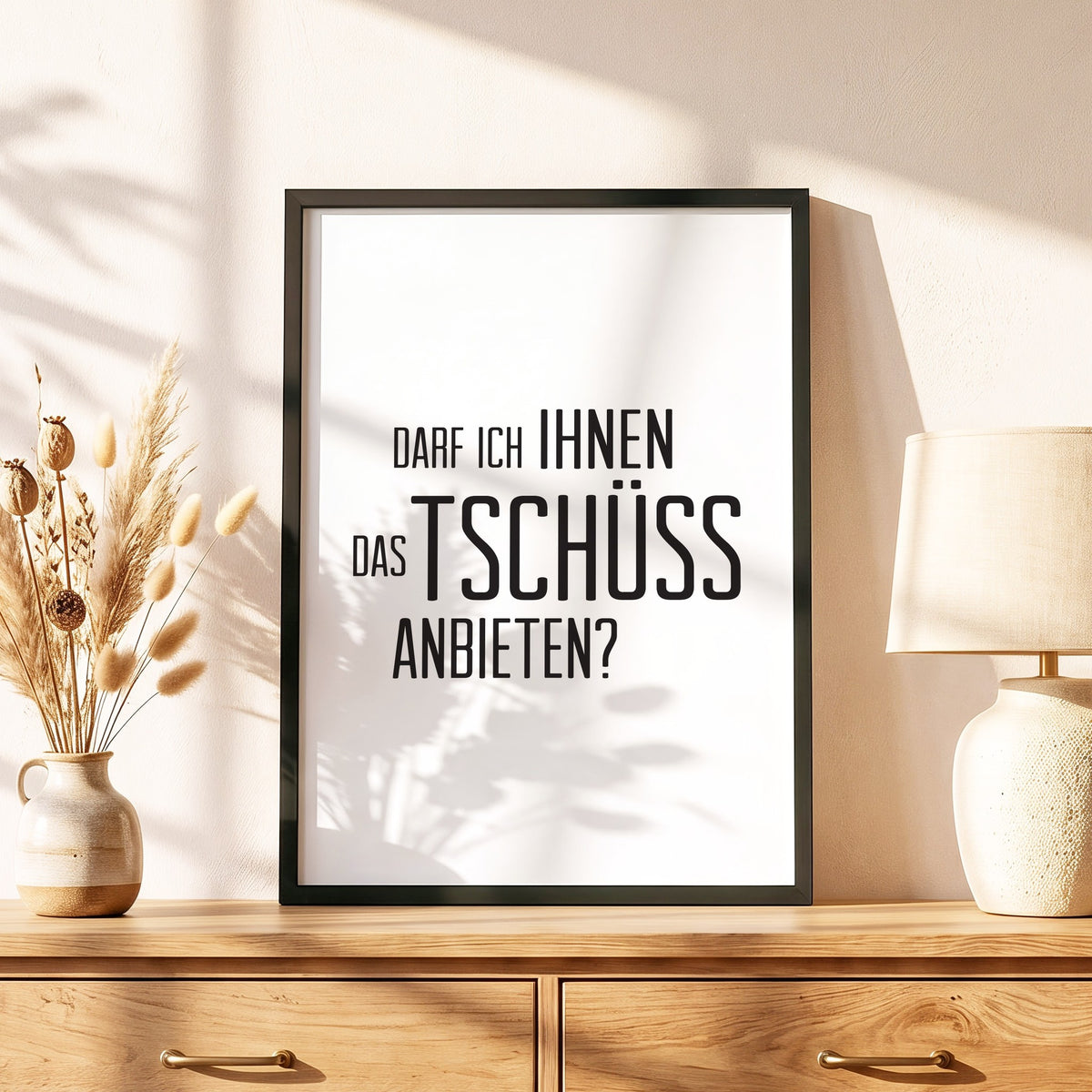 Spruchposter Darf ich Ihnen das Tschüss anbieten im schwarzen Holzrahmen auf einer Kommode