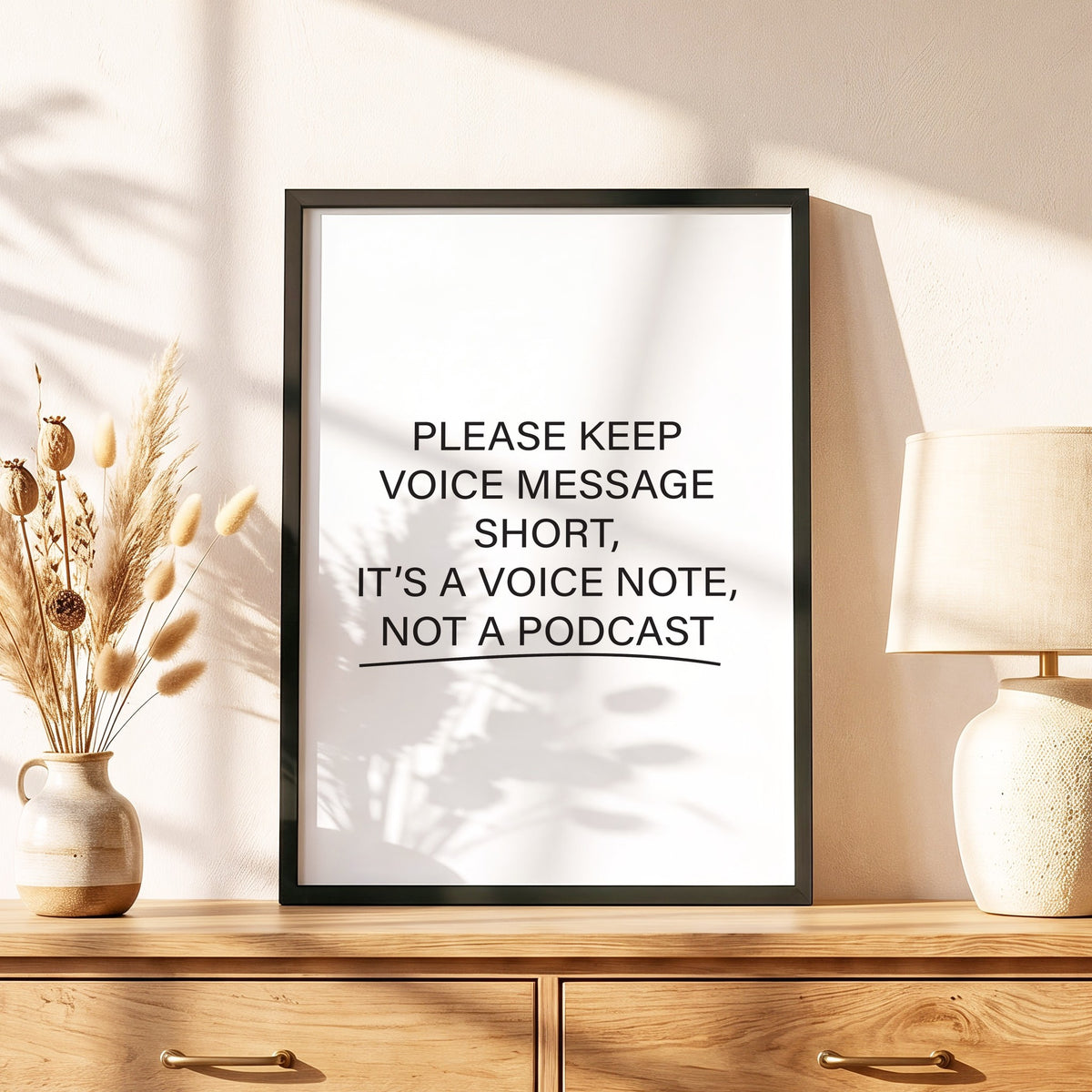 Spruchposter Please keep voice messages short im schwarzen Holzrahmen auf einer Kommode