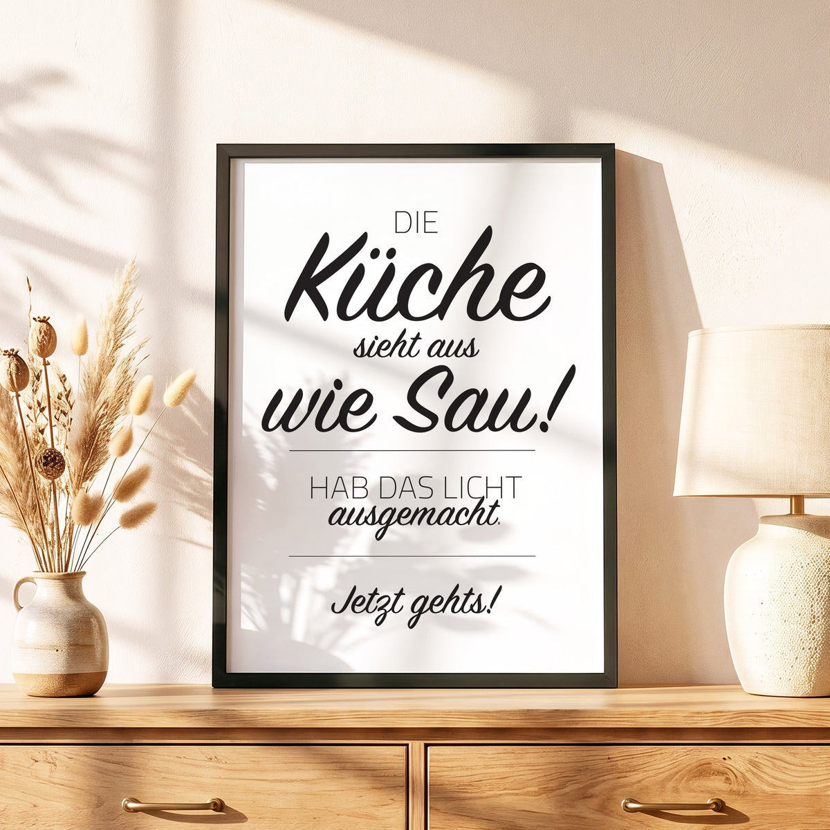 Spruchposter Die Küche sieht aus wie Sau im schwarzen Holzrahmen auf einer Kommode