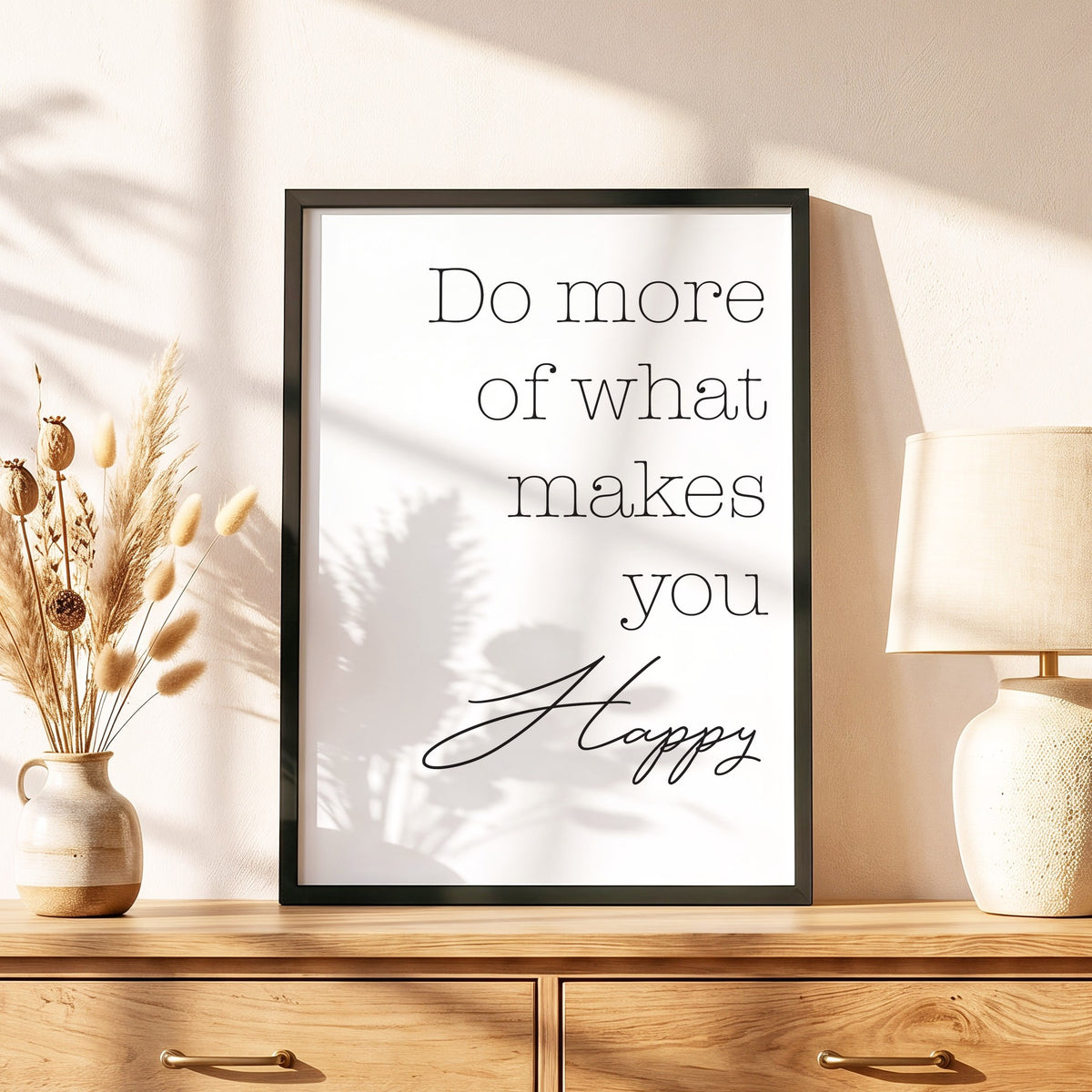 Spruchposter Do more of what makes you happy im schwarzen Holzrahmen auf einer Kommode