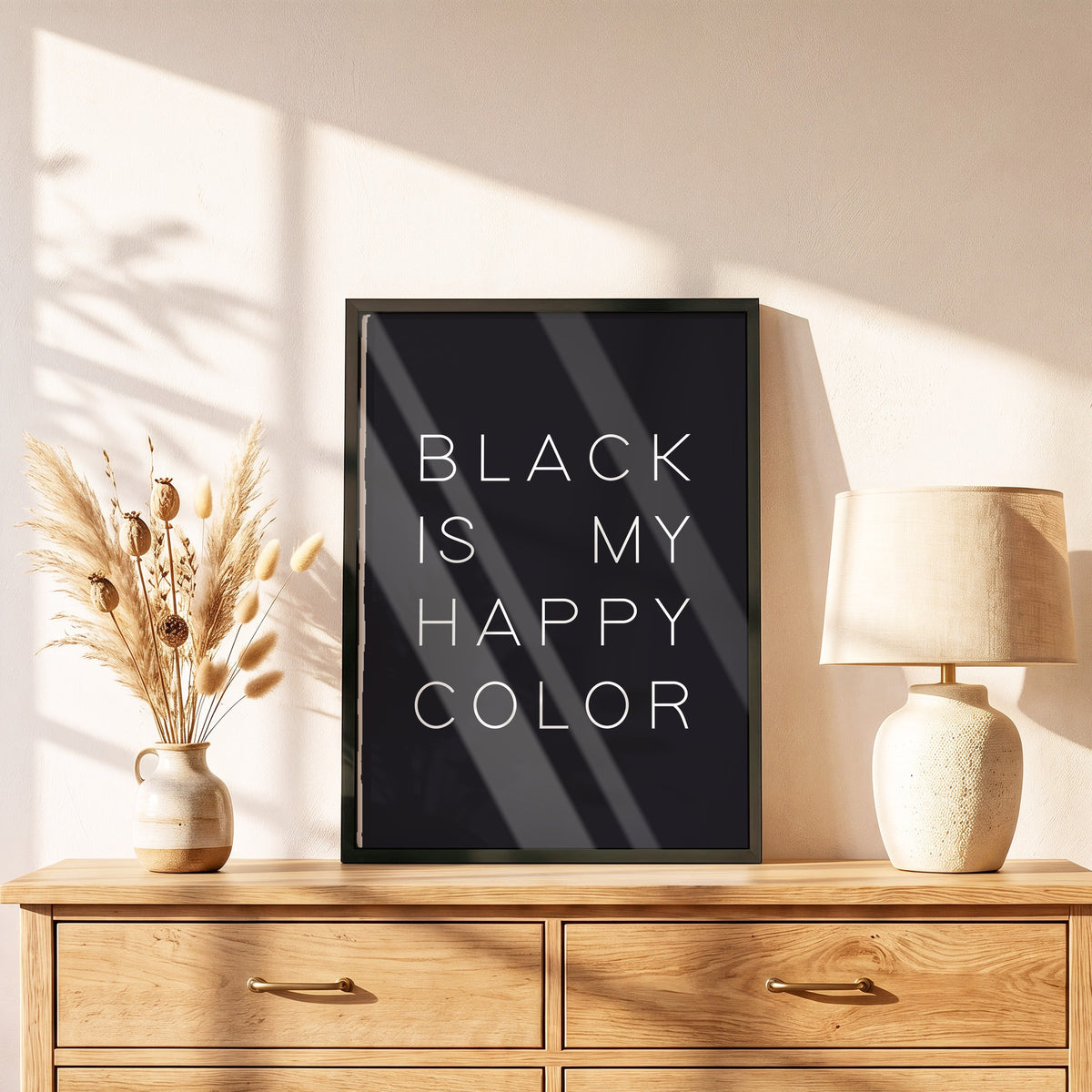 Poster Happy Color Black im schwarzen Holzrahmen auf einer Kommode
