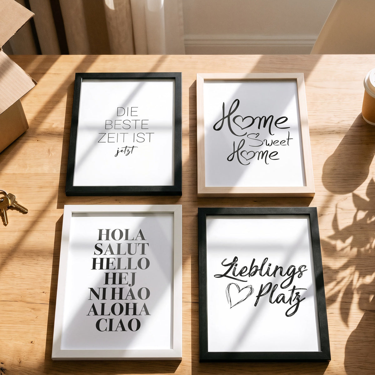 Poster Hola Salut Hello Ciao mit weiteren Motiven der Serie auf einem Tisch