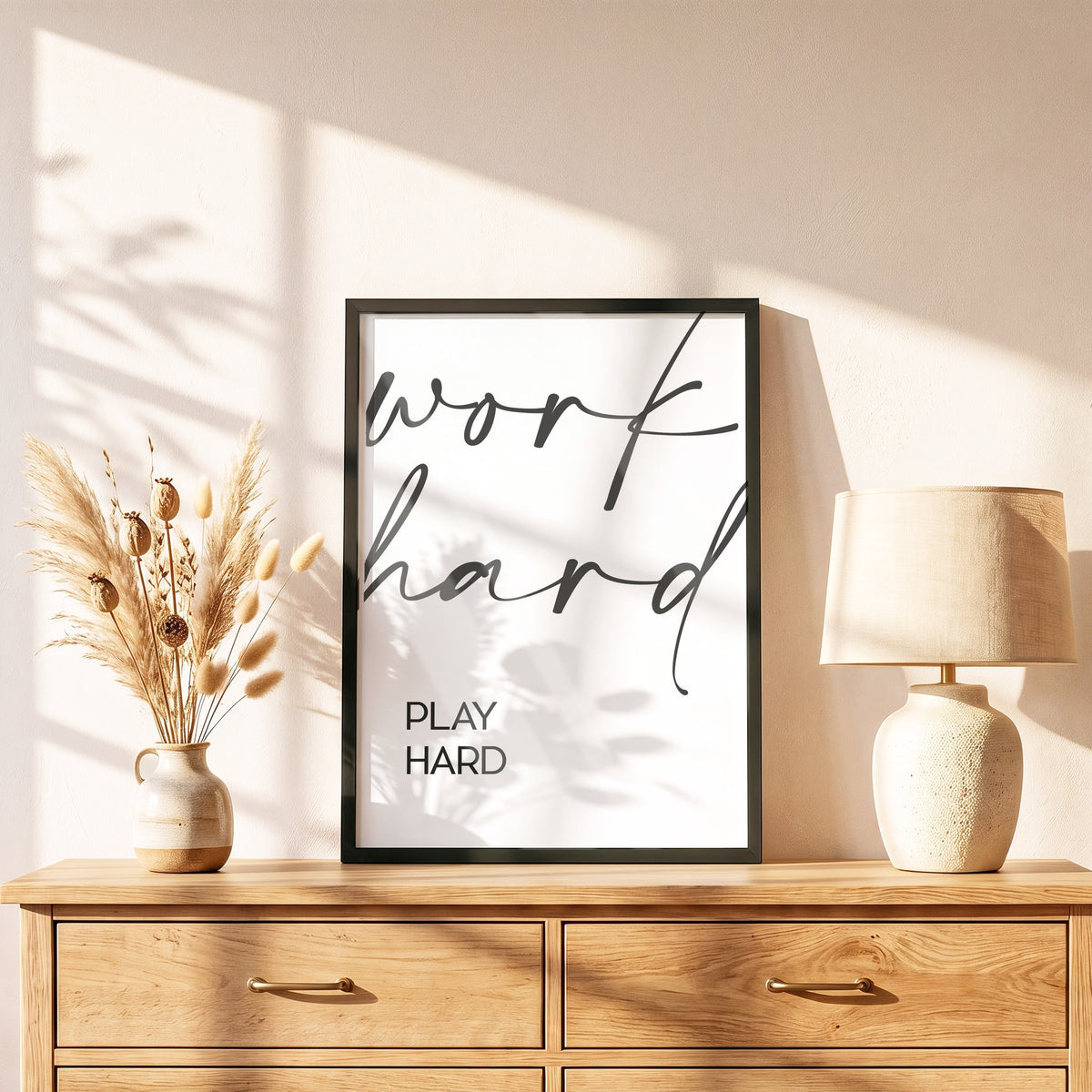 Poster Work hard, play hard im schwarzen Holzrahmen auf einer Kommode