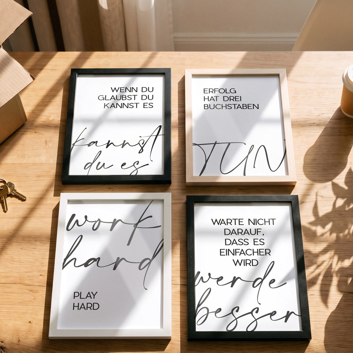 Poster Work hard, play hard mit weiteren Motiven der Serie auf einem Tisch